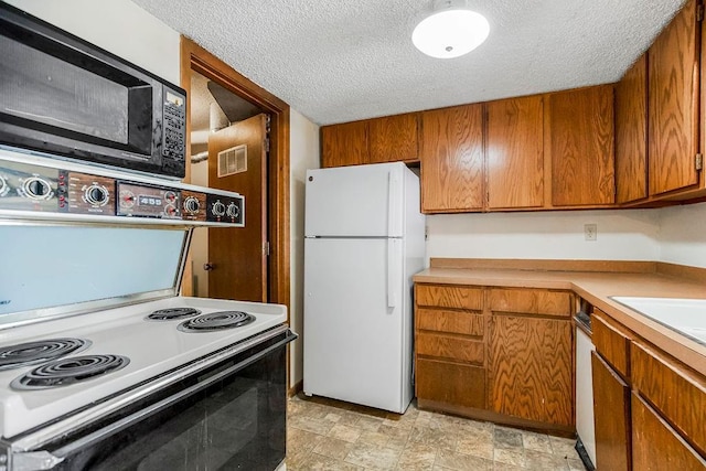 1339 Westbrooke St, Lawrence, KS 66049 - kitchen featuring freestanding refrigerator, a textured ceiling, brown cabinetry, and light countertops