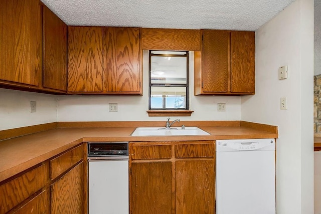 1339 Westbrooke St, Lawrence, KS 66049 - kitchen featuring white dishwasher, a sink, a textured ceiling, and brown cabinetry