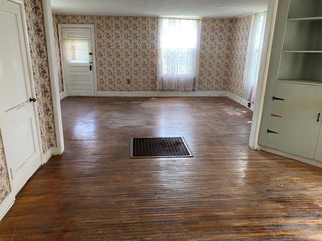 1209 S 6th St, Atchison, KS 66002 - empty room with wallpapered walls, dark wood finished floors, and baseboards