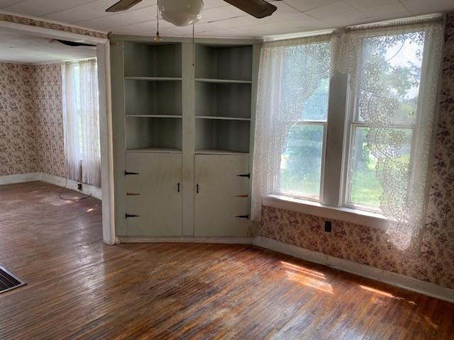 1209 S 6th St, Atchison, KS 66002 - unfurnished room featuring wallpapered walls, baseboards, wood finished floors, and a ceiling fan