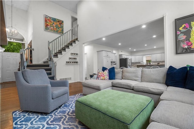 2705 W 137th Pl, Leawood, KS 66224 - living area featuring wood finished floors, a chandelier, stairs, a towering ceiling, and recessed lighting