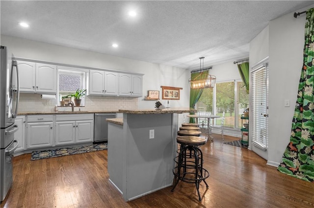 2705 W 137th Pl, Leawood, KS 66224 - kitchen featuring stainless steel appliances, a sink, a kitchen breakfast bar, decorative backsplash, and white cabinets