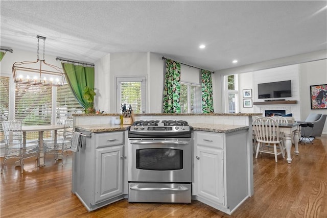 2705 W 137th Pl, Leawood, KS 66224 - kitchen with stainless steel gas stove, a chandelier, wood finished floors, white cabinets, and open floor plan