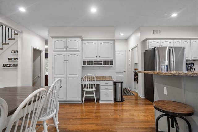 2705 W 137th Pl, Leawood, KS 66224 - kitchen with stainless steel fridge with ice dispenser, white cabinets, light stone counters, wood finished floors, and recessed lighting