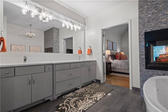 2705 W 137th Pl, Leawood, KS 66224 - bathroom with double vanity, a freestanding tub, a chandelier, ensuite bathroom, and baseboards