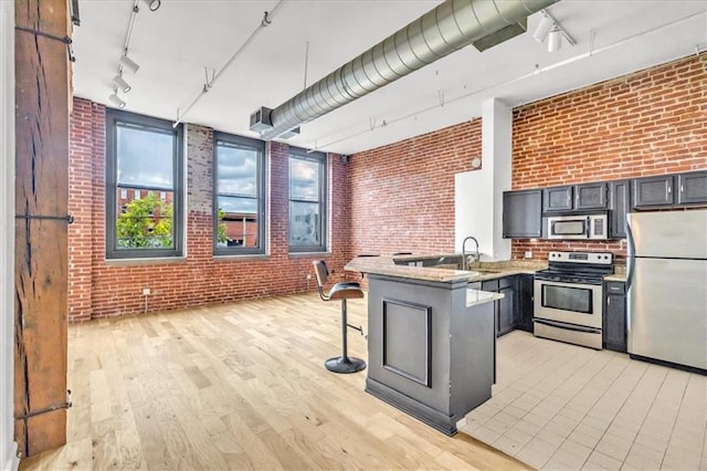 200 Main St Unit 211, Kansas City, MO 64105 - kitchen with stainless steel appliances, rail lighting, a peninsula, brick wall, and a sink
