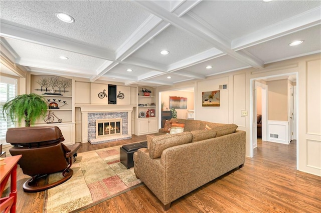 10500 Reeder St, Overland Park, KS 66214 - living room featuring wood finished floors, a glass covered fireplace, beam ceiling, coffered ceiling, and a decorative wall