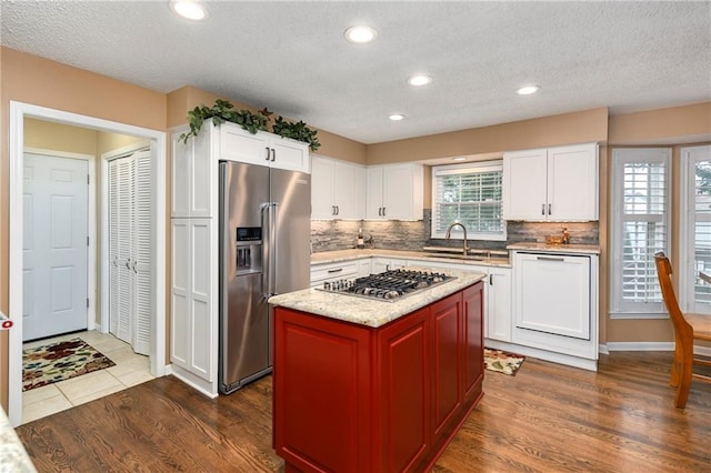 10500 Reeder St, Overland Park, KS 66214 - kitchen featuring stainless steel appliances, a sink, backsplash, white cabinetry, and a textured ceiling