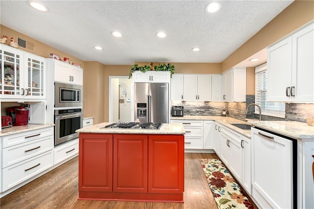 10500 Reeder St, Overland Park, KS 66214 - kitchen with appliances with stainless steel finishes, a sink, wood finished floors, a textured ceiling, and a center island