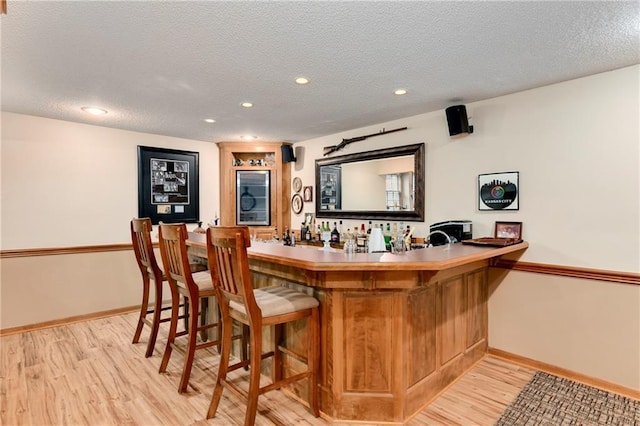 10500 Reeder St, Overland Park, KS 66214 - indoor bar featuring light wood-style flooring, a textured ceiling, baseboards, recessed lighting, and wine cooler
