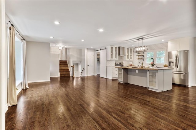 10416 Mohawk Ln, Leawood, KS 66206 - unfurnished living room with a barn door, dark wood-type flooring, recessed lighting, stairway, and baseboards