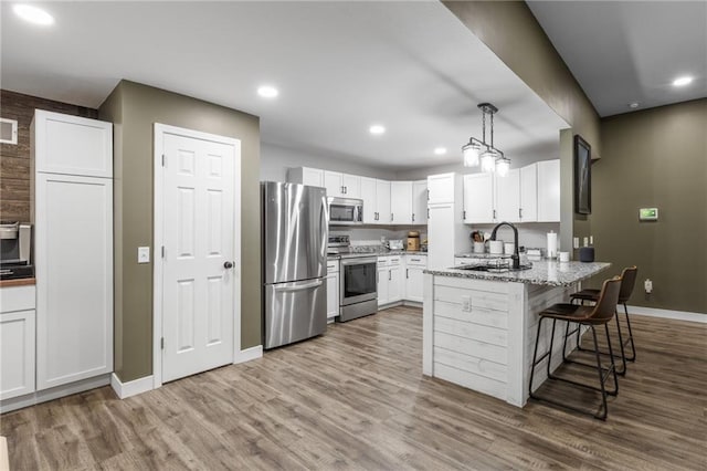 131 Cedar Ct, Warrensburg, MO 64093 - kitchen featuring appliances with stainless steel finishes, a sink, baseboards, wood finished floors, and a peninsula