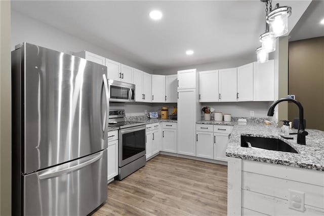 131 Cedar Ct, Warrensburg, MO 64093 - kitchen with stainless steel appliances, a sink, light stone counters, white cabinetry, and recessed lighting