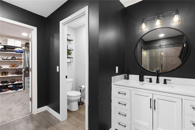 131 Cedar Ct, Warrensburg, MO 64093 - bathroom with wood finished floors, vanity, a stall shower, a walk in closet, and toilet