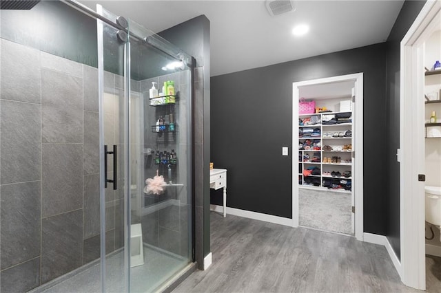 131 Cedar Ct, Warrensburg, MO 64093 - full bathroom with wood finished floors, a stall shower, a walk in closet, toilet, and baseboards