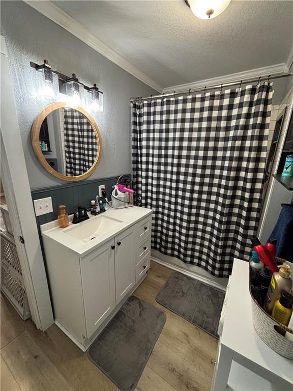 620 S Evergreen Ave, Chanute, KS 66720 - full bath with wood finished floors, crown molding, vanity, and a textured ceiling