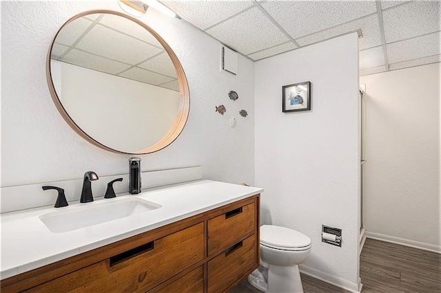 8201 W 100th Ter, Overland Park, KS 66212 - full bathroom featuring a paneled ceiling, toilet, vanity, wood finished floors, and baseboards