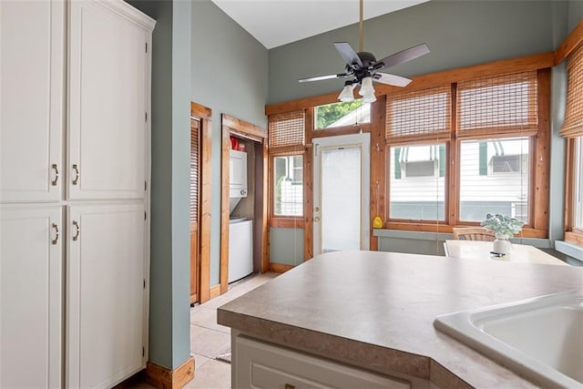 901 S 3rd St, Leavenworth, KS 66048 - kitchen featuring stacked washing machine and dryer, ceiling fan, white cabinetry, and light tile patterned floors