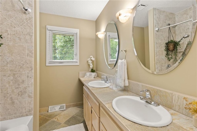 3601 NW 56th St, Houston Lake, MO 64151 - bathroom with healthy amount of natural light, double vanity, baseboards, a textured ceiling, and stone finish flooring