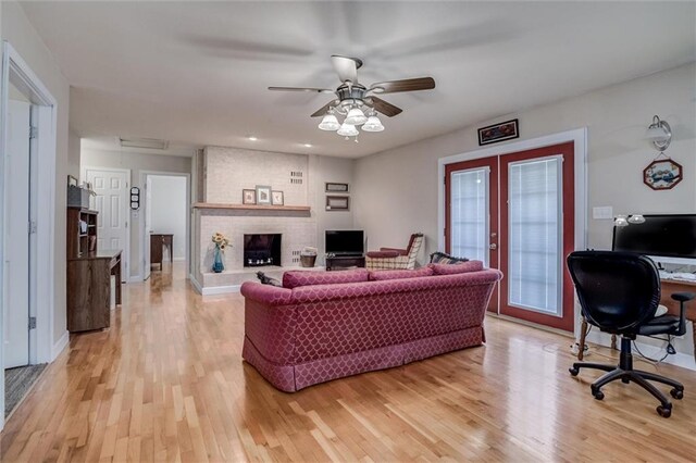 1501 Osage St, Leavenworth, KS 66048 - living room with french doors, light wood-style flooring, a desk, a ceiling fan, and a fireplace
