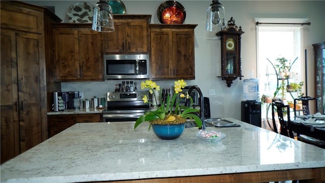 6418 N 141st St, Basehor, KS 66007 - kitchen featuring stainless steel appliances, light stone counters, decorative backsplash, a center island with sink, and a sink