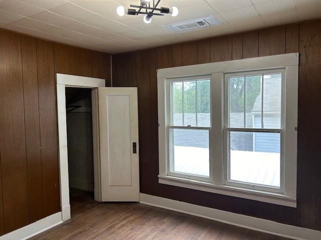 2823 Clark Ave, Parsons, KS 67357 - unfurnished bedroom featuring wooden walls, a chandelier, wood finished floors, and baseboards