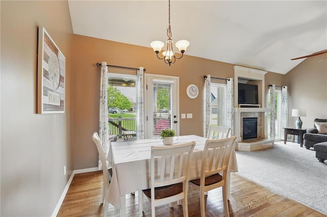 10136 N Wallace Ave, Kansas City, MO 64157 - dining room with lofted ceiling, light wood finished floors, a chandelier, a fireplace, and baseboards