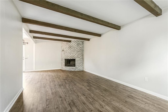 10908 Indiana Ave, Kansas City, MO 64137 - unfurnished living room with beam ceiling, wood finished floors, baseboards, and a brick fireplace