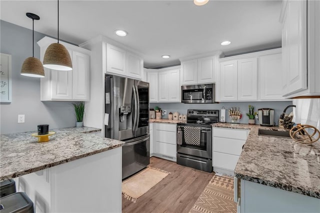 807 N Main St, Carrollton, MO 64633 - kitchen with stainless steel appliances, a sink, white cabinetry, light stone counters, and light wood-style floors
