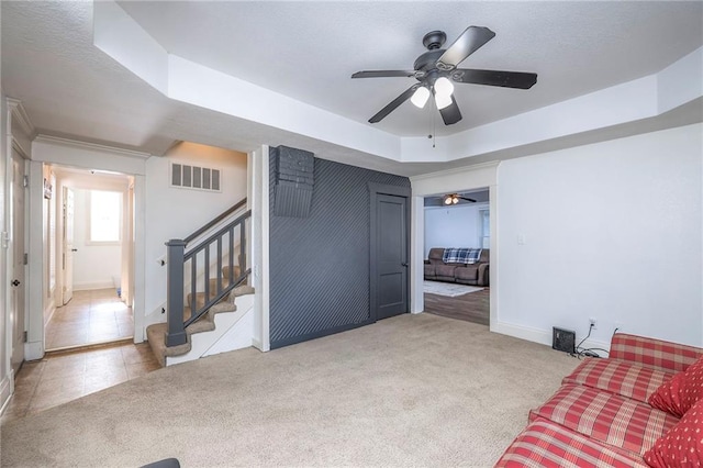 1101 S Independence St, Harrisonville, MO 64701 - living area featuring carpet floors, ceiling fan, a raised ceiling, and stairs