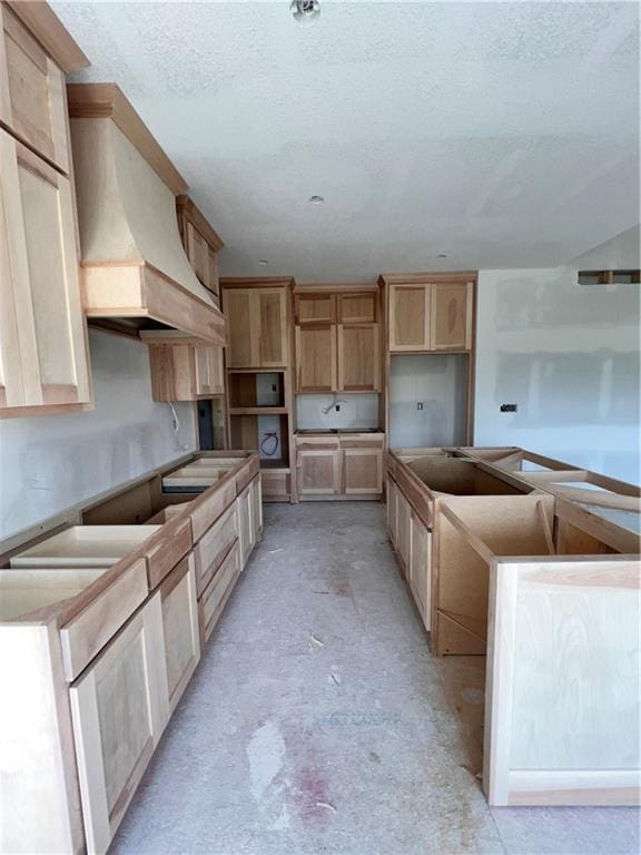 16500 Ingalls St, Gardner, KS 66030 - kitchen with custom range hood, unfinished concrete flooring, light brown cabinetry, and a textured ceiling