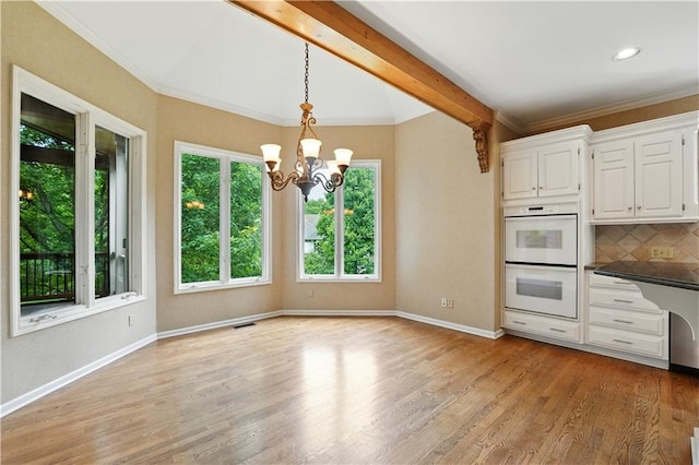 13905 Lucille St, Overland Park, KS 66221 - kitchen with white double oven, a chandelier, backsplash, white cabinets, and hanging light fixtures