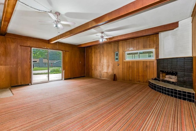1036 Vilas St, Leavenworth, KS 66048 - unfurnished living room with beam ceiling, a fireplace, wood walls, ceiling fan, and carpet flooring