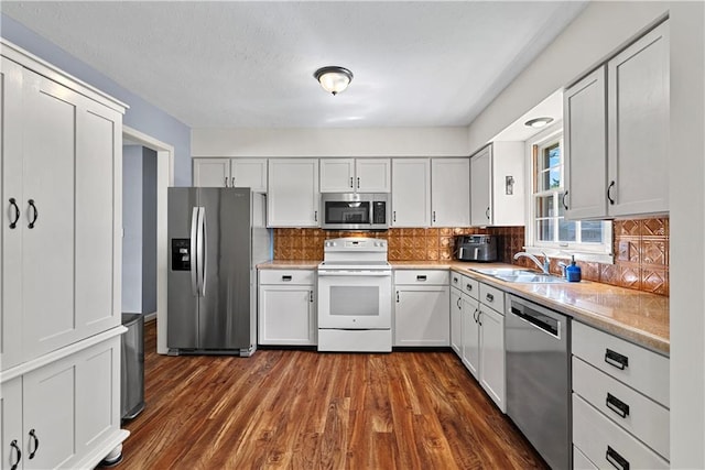 522 Kasold Dr, Lawrence, KS 66049 - kitchen featuring stainless steel appliances, a sink, dark wood-style flooring, light countertops, and backsplash
