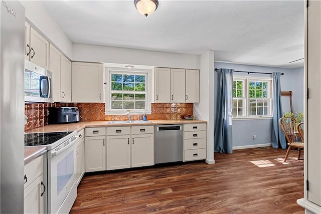 522 Kasold Dr, Lawrence, KS 66049 - kitchen with appliances with stainless steel finishes, a sink, dark wood-style floors, light countertops, and backsplash