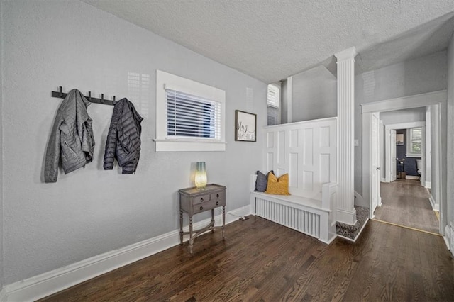 1316 E 42nd St, Kansas City, MO 64110 - corridor featuring wood finished floors, baseboards, a textured ceiling, and decorative columns