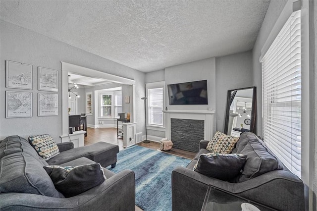 1316 E 42nd St, Kansas City, MO 64110 - living area featuring a fireplace with flush hearth, a textured ceiling, wood finished floors, a textured wall, and baseboards
