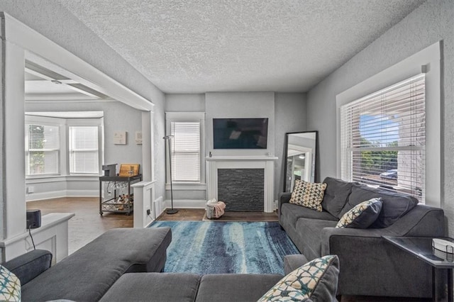 1316 E 42nd St, Kansas City, MO 64110 - living room featuring a fireplace, plenty of natural light, a textured ceiling, and wood finished floors