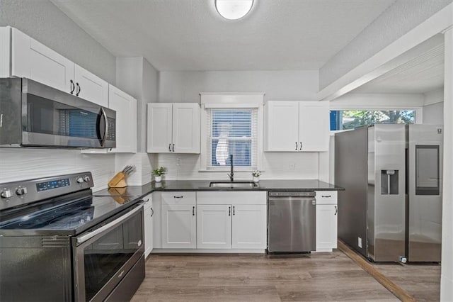1316 E 42nd St, Kansas City, MO 64110 - kitchen featuring stainless steel appliances, a sink, white cabinetry, dark countertops, and a textured ceiling