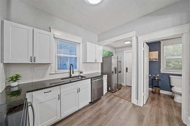 1316 E 42nd St, Kansas City, MO 64110 - kitchen featuring stainless steel appliances, a sink, light wood-type flooring, baseboards, and white cabinets