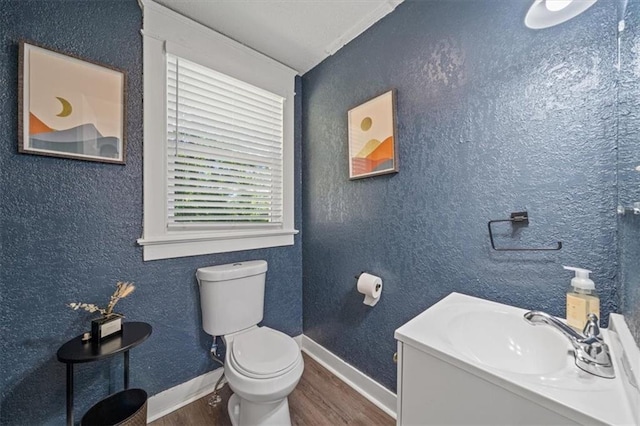 1316 E 42nd St, Kansas City, MO 64110 - bathroom with wood finished floors, a sink, toilet, and baseboards