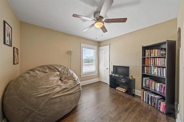 1316 E 42nd St, Kansas City, MO 64110 - sitting room with wood finished floors, ceiling fan, a textured ceiling, a textured wall, and baseboards