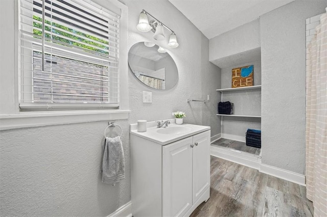 1316 E 42nd St, Kansas City, MO 64110 - bathroom featuring a textured wall, wood finished floors, vanity, and baseboards