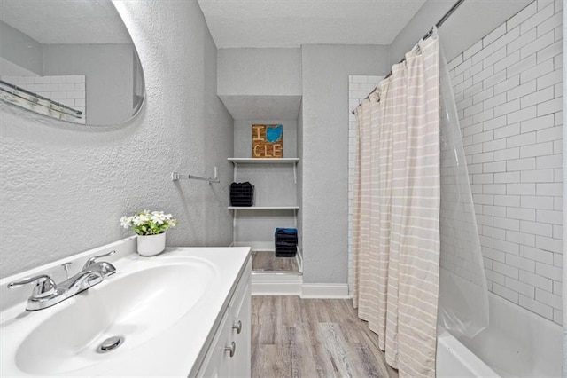 1316 E 42nd St, Kansas City, MO 64110 - full bath featuring a textured wall, wood finished floors, vanity, shower / tub combo, and a textured ceiling