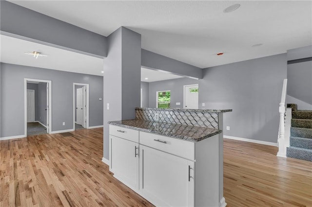 2311 Shawnee Dr, Kansas City, KS 66106 - kitchen with light wood-style floors, white cabinets, baseboards, and dark stone counters