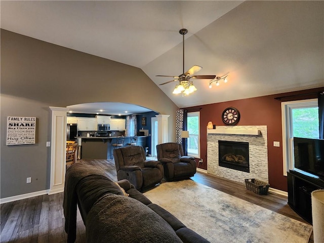 9001 NE 109th Ter, Kansas City, MO 64157 - living room featuring ceiling fan, arched walkways, decorative columns, vaulted ceiling, and dark wood-type flooring