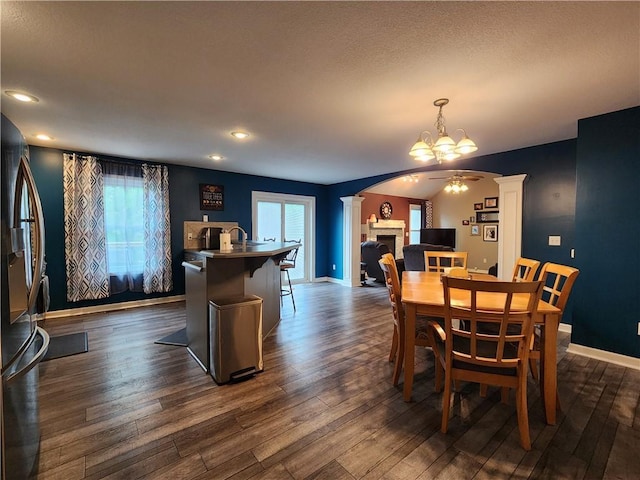 9001 NE 109th Ter, Kansas City, MO 64157 - dining space featuring decorative columns, a chandelier, dark wood-style flooring, baseboards, and a fireplace