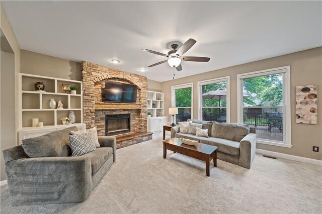 14450 W 146th Ter, Olathe, KS 66062 - living area with ceiling fan, a stone fireplace, light colored carpet, and baseboards