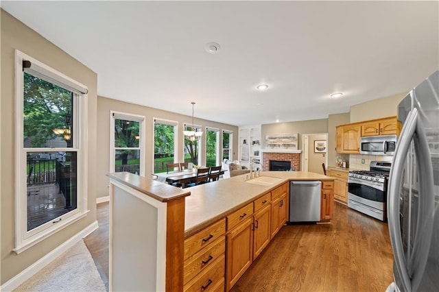14450 W 146th Ter, Olathe, KS 66062 - kitchen with stainless steel appliances, a sink, light countertops, a fireplace, and an island with sink