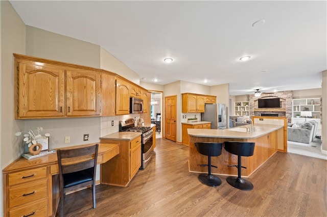 14450 W 146th Ter, Olathe, KS 66062 - kitchen featuring appliances with stainless steel finishes, wood finished floors, a kitchen bar, a sink, and open floor plan